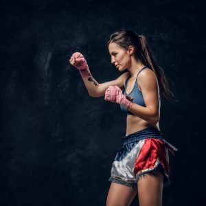 Beautiful sportive woman is warming up before training while posing for photographer.